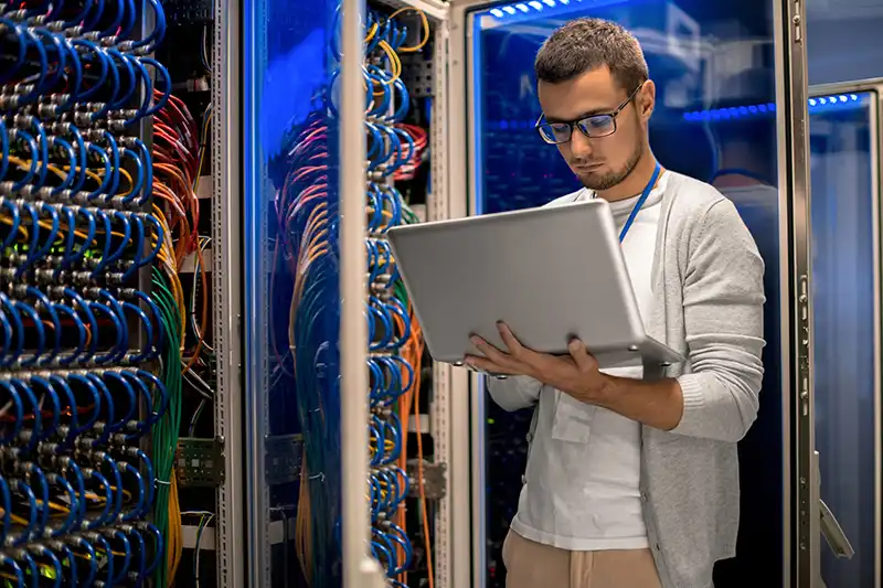 Mensch mit Computer in Serverraum